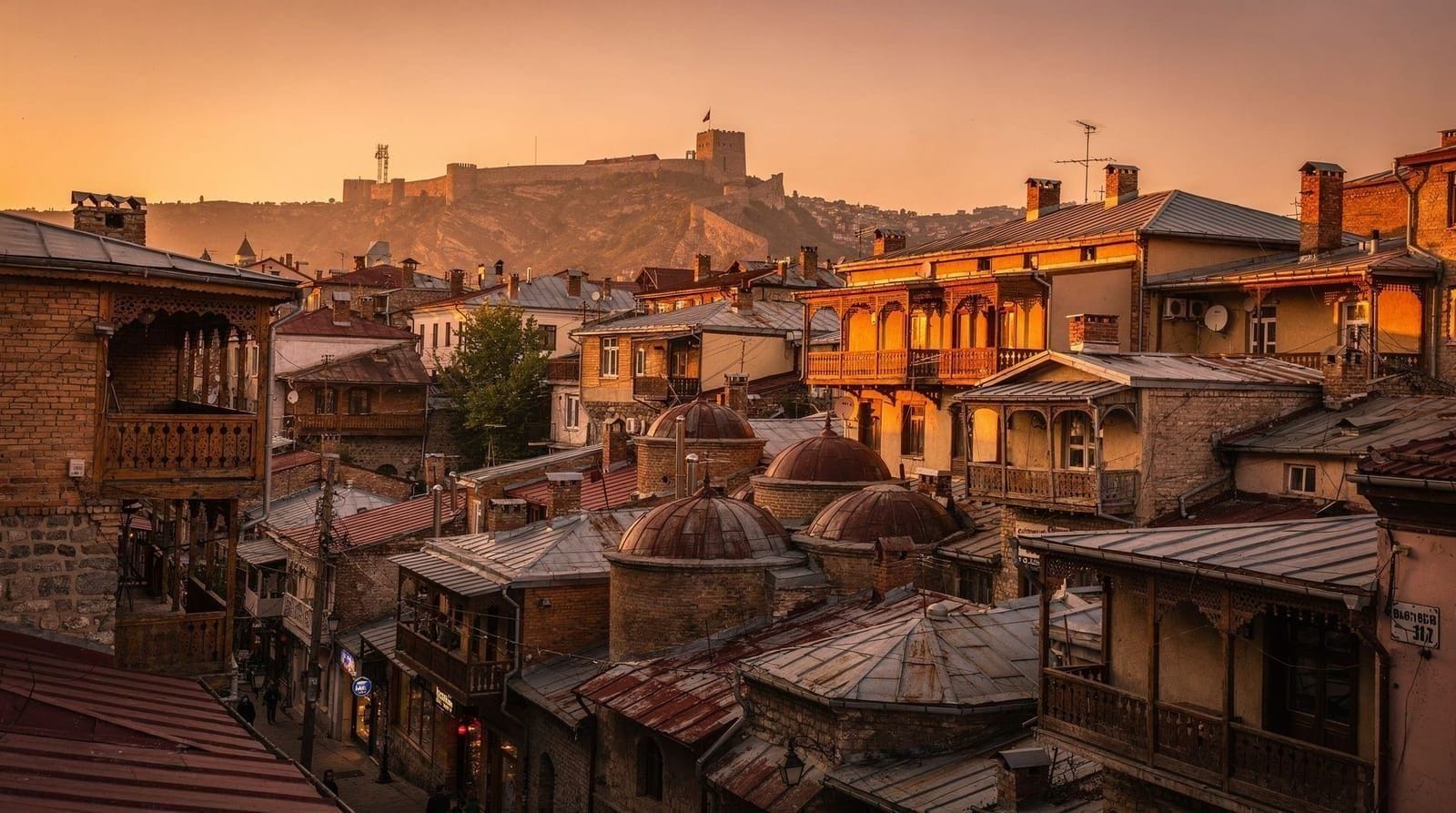 Tbilisi's Old Town rooftops and sulphur bathhouses beneath Narikala fortress at dusk